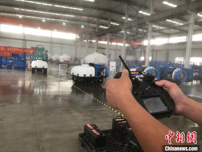 一名工人拿著遙感器，指揮機(jī)器人進(jìn)行“農(nóng)藥”噴灑作業(yè)。　劉林 攝