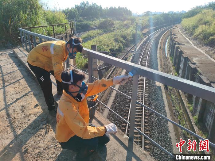 圖為高溫下南寧工務(wù)段橋梁工全副武裝對鐵路橋梁人行道欄桿打磨除銹?！●T博 攝