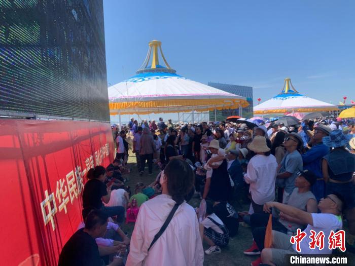 圖為沒有擠進(jìn)座位席的人們，在會(huì)場一側(cè)的大屏幕下觀看演出?！W藍(lán) 攝