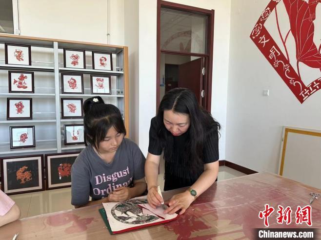 圖為胡穎指導(dǎo)學(xué)員學(xué)習(xí)剪紙藝術(shù)?！罹靶?攝