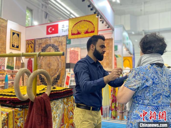 土耳其國家館工作人員向游客展示當?shù)匚膭?chuàng)產品。中新社記者張瑋攝
