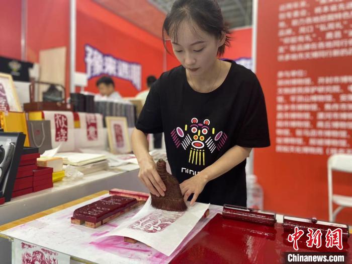 7月14日，周口華威民俗文化博物苑的講解員杜奧杰在文博會現(xiàn)場展示拓印。中新社記者張瑋攝