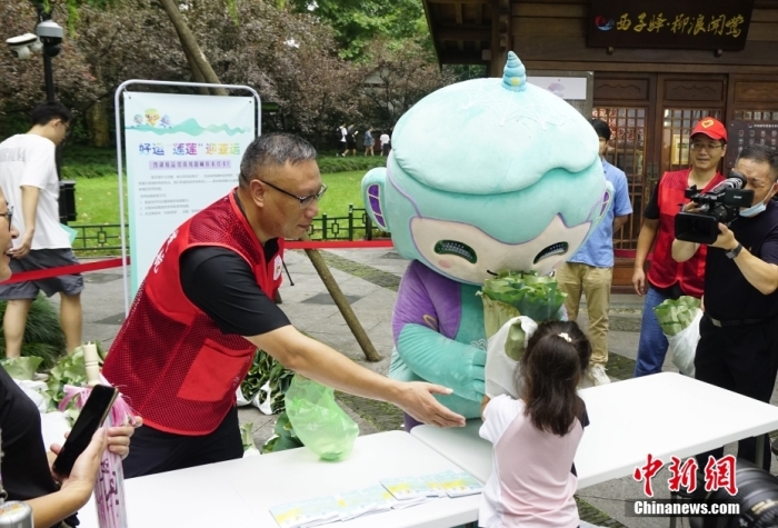 杭州亞運會吉祥物“琮琮”“宸宸”“蓮蓮”在浙江杭州西湖畔參加蓮蓬荷葉義賣活動，圖為亞運會吉祥物“蓮蓮”將分包好的蓮蓬、荷葉交給顧客。<a target='_blank' href='/'>中新社</a>發(fā) 王瓊苓 攝