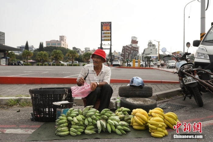 資料圖：臺灣花蓮市區(qū)博愛路早市，商販在街頭擺攤售賣水果，不遠處是因震傾斜嚴重的天王星大樓。 中新社記者 楊程晨 攝.jpg
