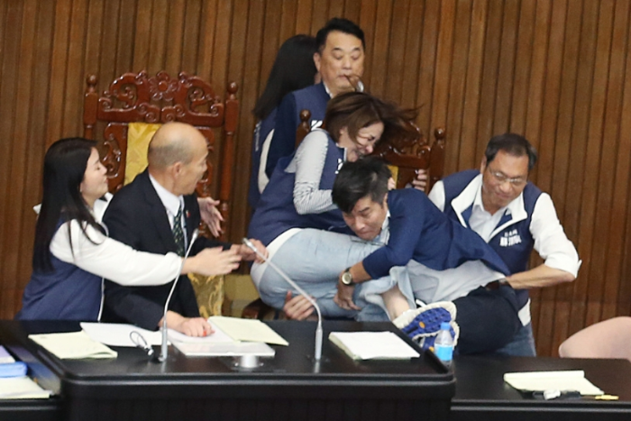 民進(jìn)黨立法委員鐘佳濱（右二）趁著表決的空擋沖上主席臺(tái)，國(guó)民黨陳菁徽（右三）擋在主席臺(tái)前被鐘佳濱撲倒