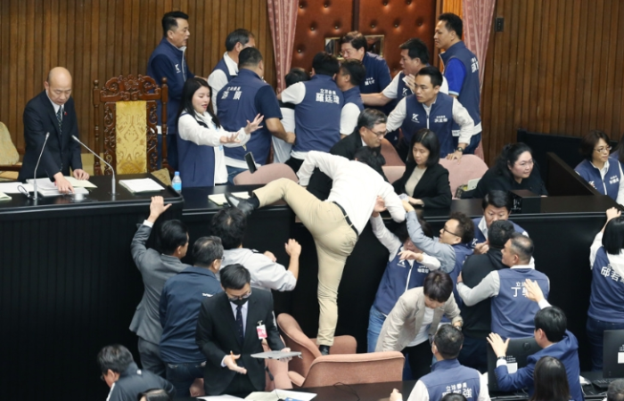 民進(jìn)黨立委郭國(guó)文（中背影者）卻翻上桌，遭國(guó)民黨立委攔阻