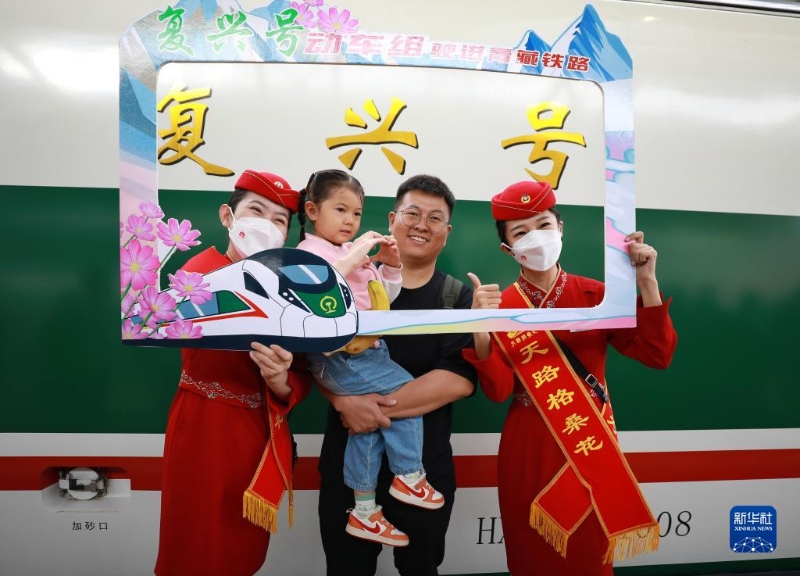 2023年7月1日，乘客與乘務(wù)人員在西寧至格爾木動(dòng)車(chē)組首發(fā)列車(chē)前合影留念。（圖源：新華社）
